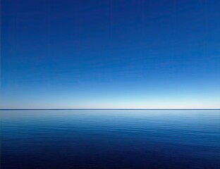 Tranquil expanse of a vast, serene blue ocean meeting a cloudless blue sky