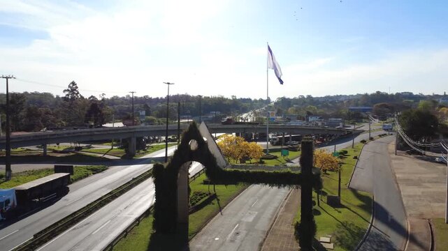 Entrada da cidade de Ponta Grossa P&oacute;rtico Bairro Car&aacute;-Car&aacute; com mastro e bandeira da cidade carros passando na estrada