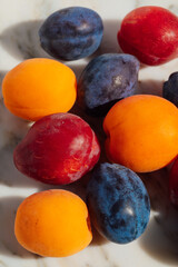 apricots, plums on white marble