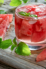 Watermelon cold drink with mint on an old wooden background with slices of ripe watermelon