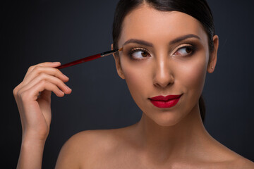 Fototapeta premium Beautiful young woman with tanned skin and professional makeup with red lips. Spa, wellness and skin care.