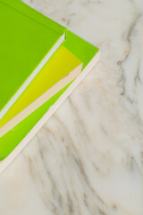 pile of three books with neon green covers on white marble table
