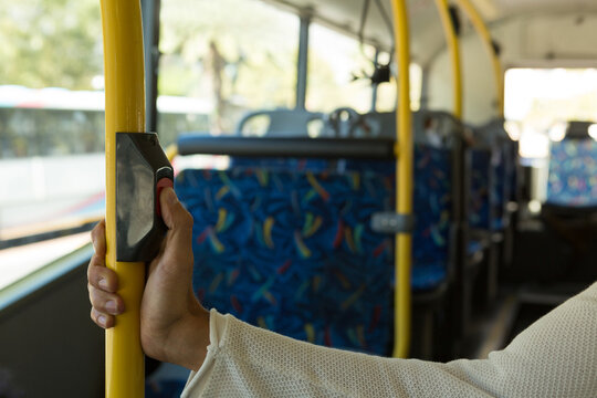 Female passenger tapping electronic fare card reader on yellow handrail inside city bus, copy space