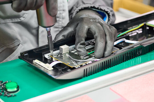 Expert technician assembling printed circuit board into plastic housing in an electronics manufacturing facility