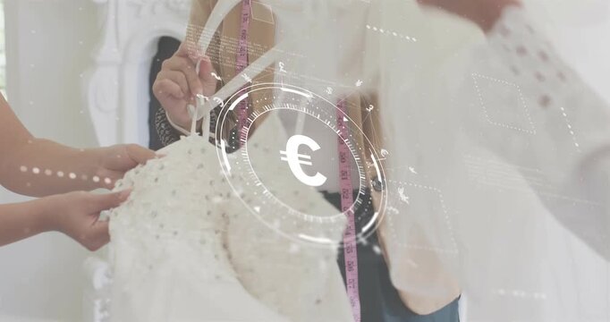 Seamstress selecting beaded dress with euro HUD as client adjusting hemline for fashion fitting