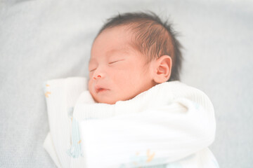 ベッドで眠る新生児0ヶ月の赤ちゃん