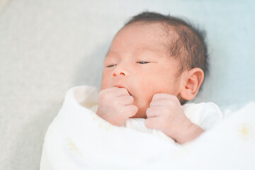 ベッドで眠る新生児0ヶ月の赤ちゃん