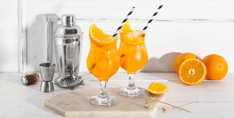 Glasses of Aperol spritz cocktail with oranges and shaker on white wooden table