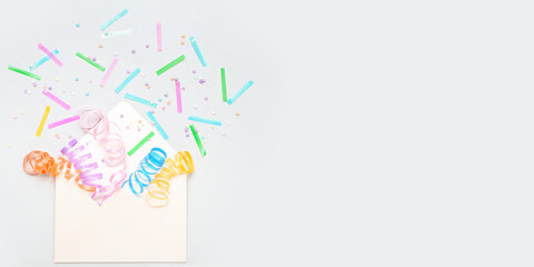 Envelope with serpentine and confetti on light background