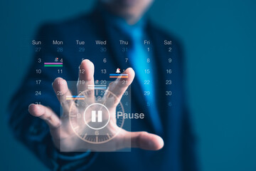 Businessman touching pause symbol on digital calendar interface for time off, project delay, or work-life balance management concept