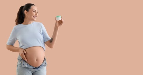 Happy young pregnant woman with body cream on beige background with space for text
