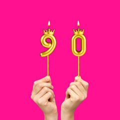 Birthday on a fuchsia background with the number 90 - Hands holding number-shaped candles
