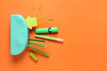 Blue pencil case with different stationery on orange background. Top view