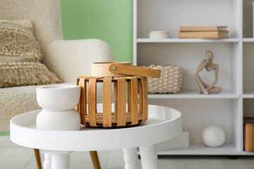Coffee table with vase and lantern near green wall in room. Closeup