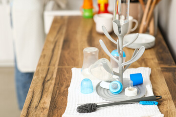 Drying rack for baby bottles and cleaning brush on counter in kitchen, closeup