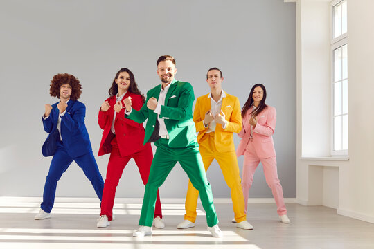 Fototapeta Team of happy professional dancers rehearsing new choreography together. Group of cheerful, smiling, young people wearing colorful suits dancing in modern white dance studio