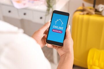 Female tourist with phone at home, closeup. Concept of online booking