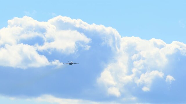 Approaching F-18 fighter jet flying beneath the clouds, showcasing military strength, speed, and precision. Slow motion view