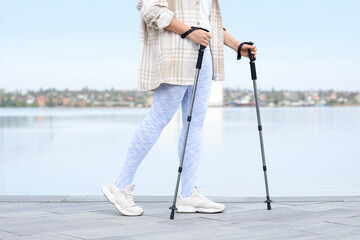 Sporty woman doing Nordic walking on embankment
