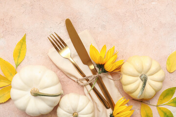Stylish cutlery with autumn leaves, beautiful flowers and fresh pumpkins on beige background
