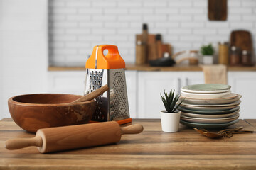 Different utensils and houseplant on wooden table in kitchen