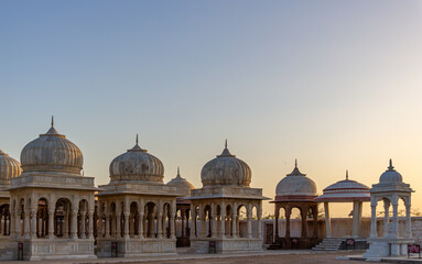 Obraz premium Ancient Stone Cenotaphs with Ornate Domes and Pillars Under a Clear, Golden Sunset Sky