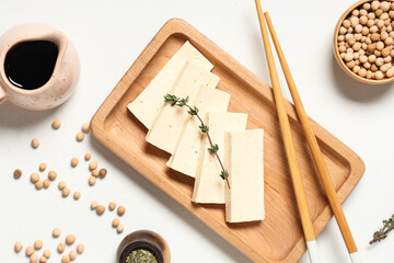 Composition with tray, slices of tasty tofu cheese, chopsticks and chickpeas on white background