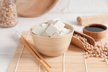 Bowl with pieces of tofu cheese on white background