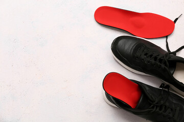 Shoes with orthopedic insoles on light background with space for text
