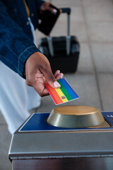 Tourist using rainbow credit card at subway station turnstile