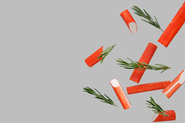 Tasty crab sticks and rosemary flying on grey background © Pixel-Shot