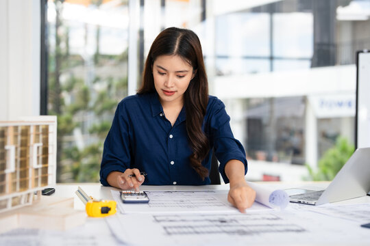 Civil Engineer working on shop drawings of  post tension slab plan on desk with Calculator and triangular scale in construction site office .