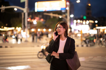 Businesswoman talking on phone walking urban night street