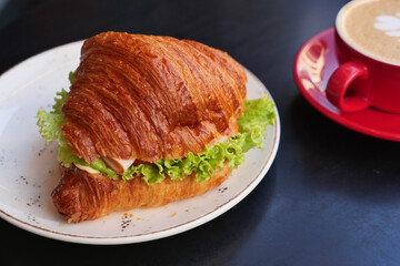 Fresh croissant sandwich with coffee in a cafe setting