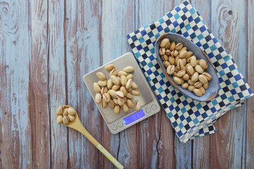 Measuring pistachios on a kitchen scale with a wooden spoon