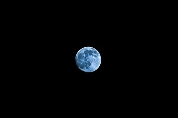 Full bluish moon against a black sky