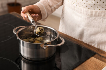 Woman boiling quail eggs in saucepot on stove