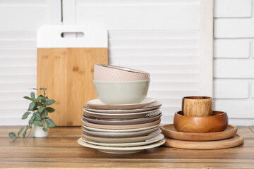 Stacks of plates and bowls on counters near white brick wall in kitchen