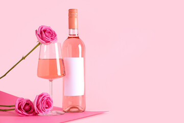 Glass and bottle of pink wine with beautiful roses on color background