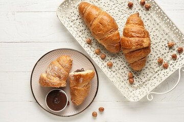 Tray with sweet chocolate croissants and hazelnuts on white wooden background