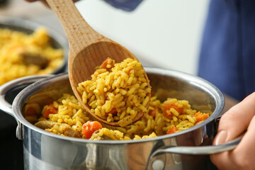 Woman preparing pilaf in cooking pot, closeup