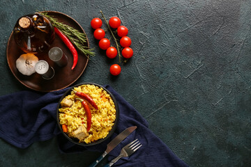 Bowl with tasty pilaf and ingredients on dark background