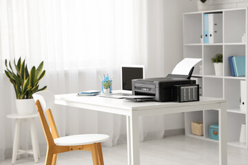 Stylish workplace with modern printer and laptop in light home office