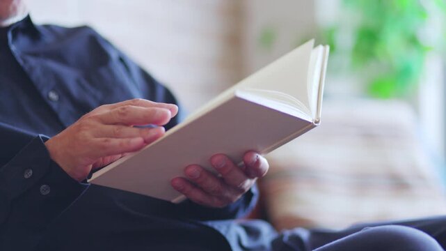 Senior Japanese man reading a book in the living room