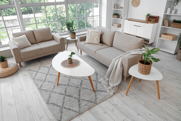 Interior of living room with plants in wicker baskets, sofas and tables