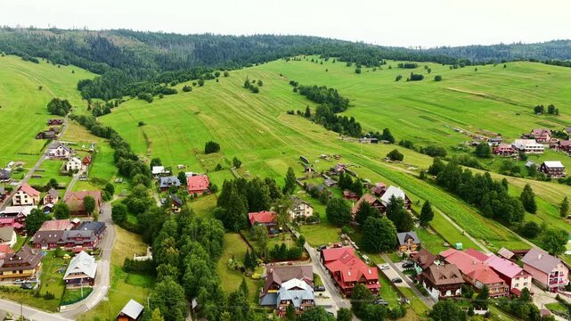 Drone footage of Osturňa village in northern Slovakia, showcasing traditional houses, green meadows, and rolling hills in summer. Peaceful rural life in the heart of nature.