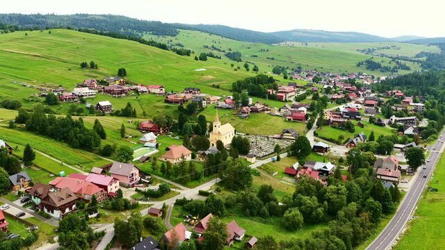 Drone footage of Osturňa village in northern Slovakia, showcasing traditional houses, green meadows, and rolling hills in summer. Peaceful rural life in the heart of nature. (4K)