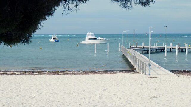 Beautiful expensive powerboat prepares to dock at beachside jetty on Rottnest Island, Australia