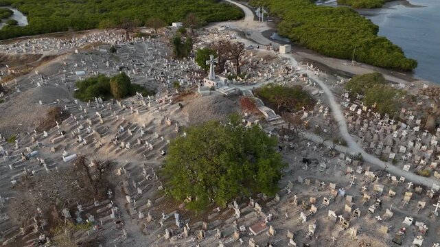 Aerial drone of Joal Fadiouth shell cemetery in Senegal, sacred interfaith burial ground built on seashells, surrounded by lagoon and mangroves