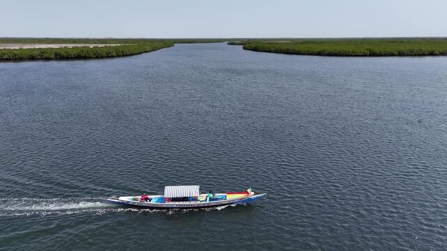 Drone aerial view of a boat crossing the wide river in Sine Saloum Delta, Senegal. Scenic natural wetlands and mangroves in UNESCO protected biosphere reserve